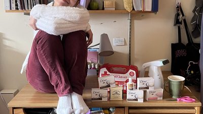 Lexi sits on her desk, surrounded by various things she brought to college